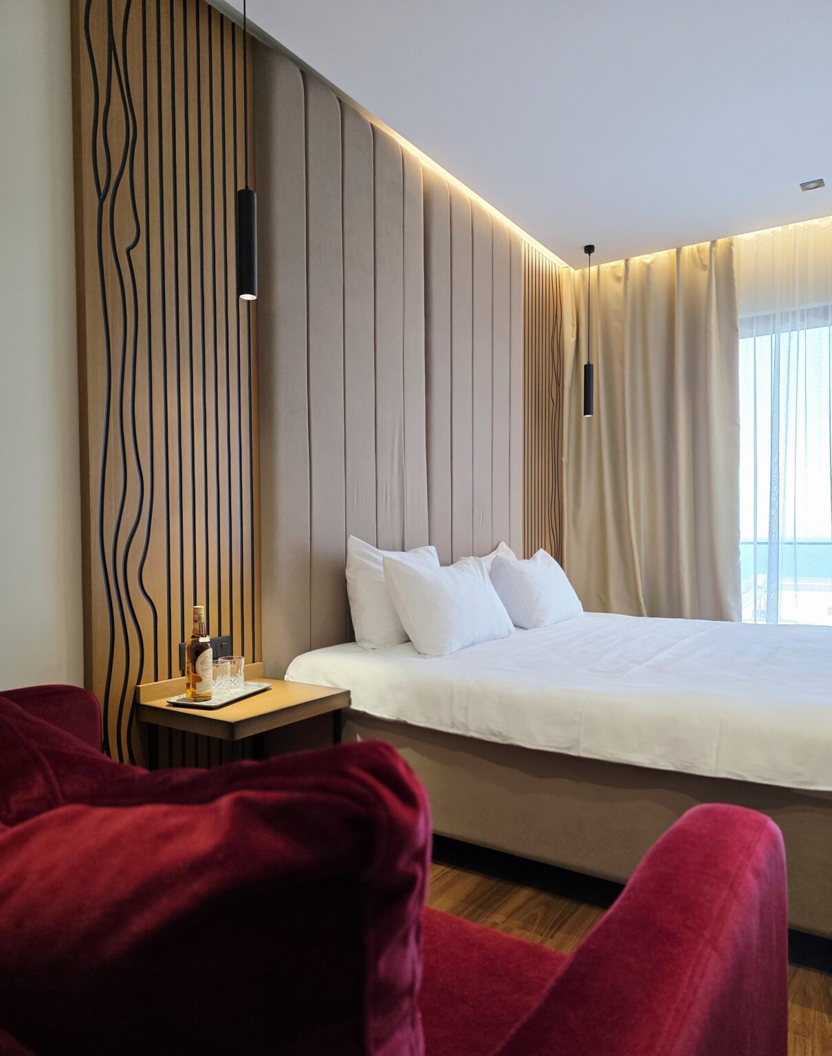 Double bed and pendant lights, the sea glimpsed through sheer curtains, Valza Boutique Hotel, Vlorë