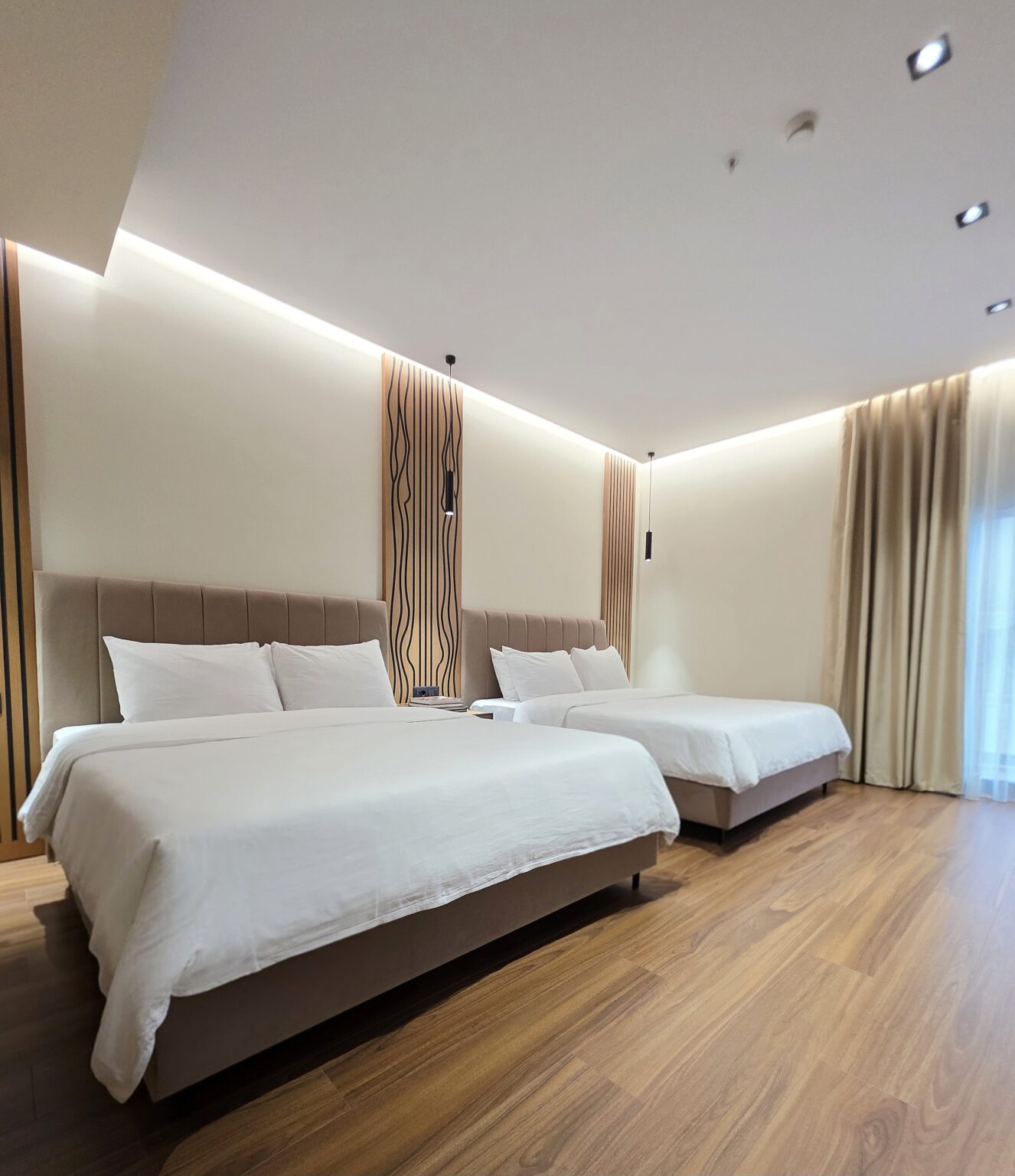 Double Twin Room with two double beds, beige padded headboards, wood slat panels and pendant lights