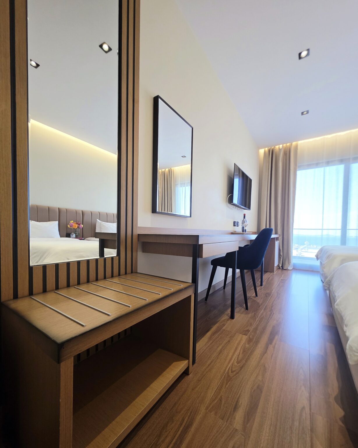 Double Deluxe Room with Extra Bed at Valza Boutique Hotel: wooden desk, wall-mounted TV, mirrors and a hazy sea view