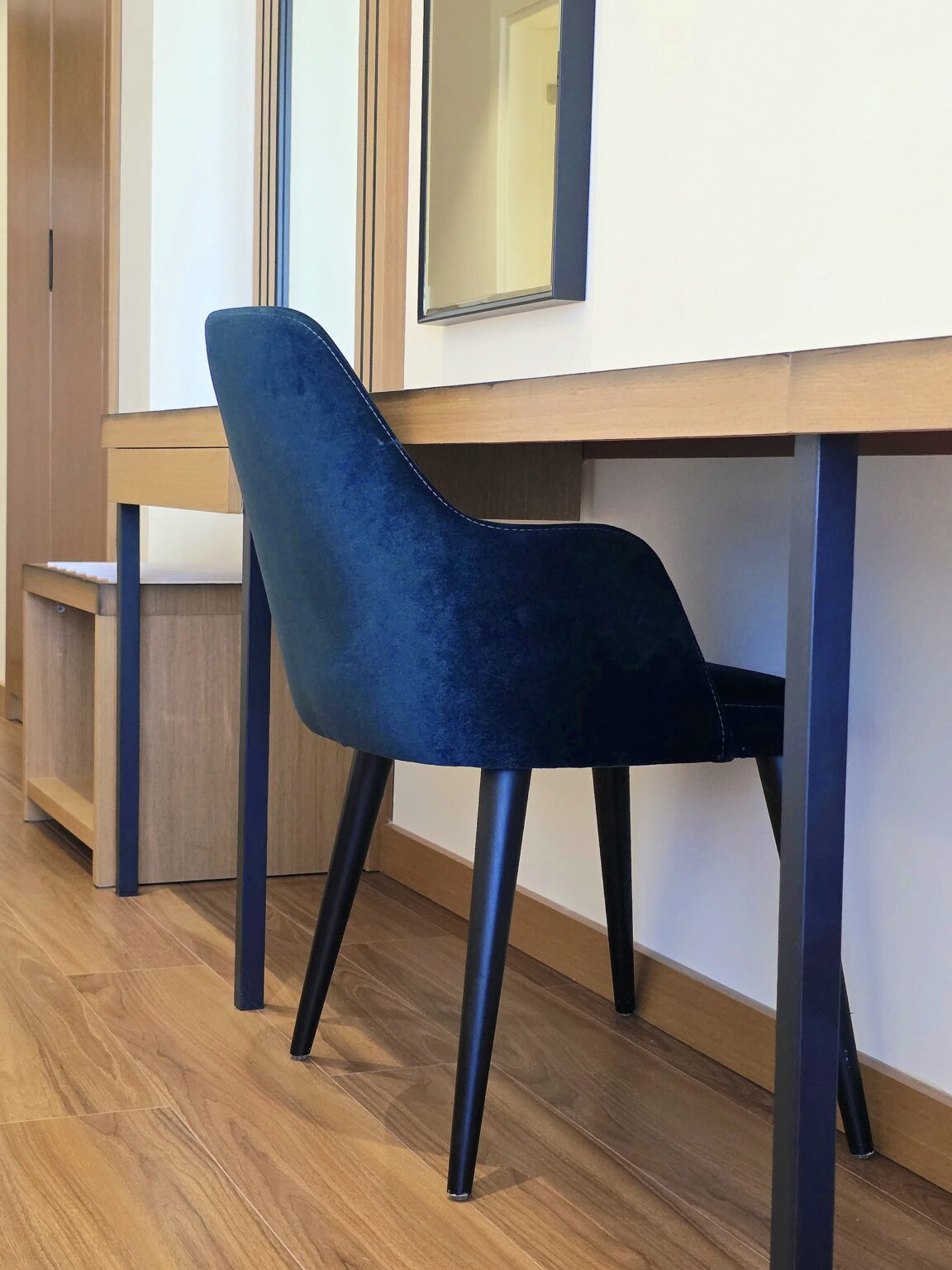 Navy blue velvet chair tucked under the wooden desk in the Double Deluxe Room with Extra Bed