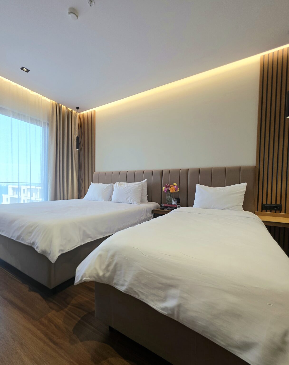 Double Deluxe Room with Extra Bed: king-size bed and a single bed under one long padded headboard