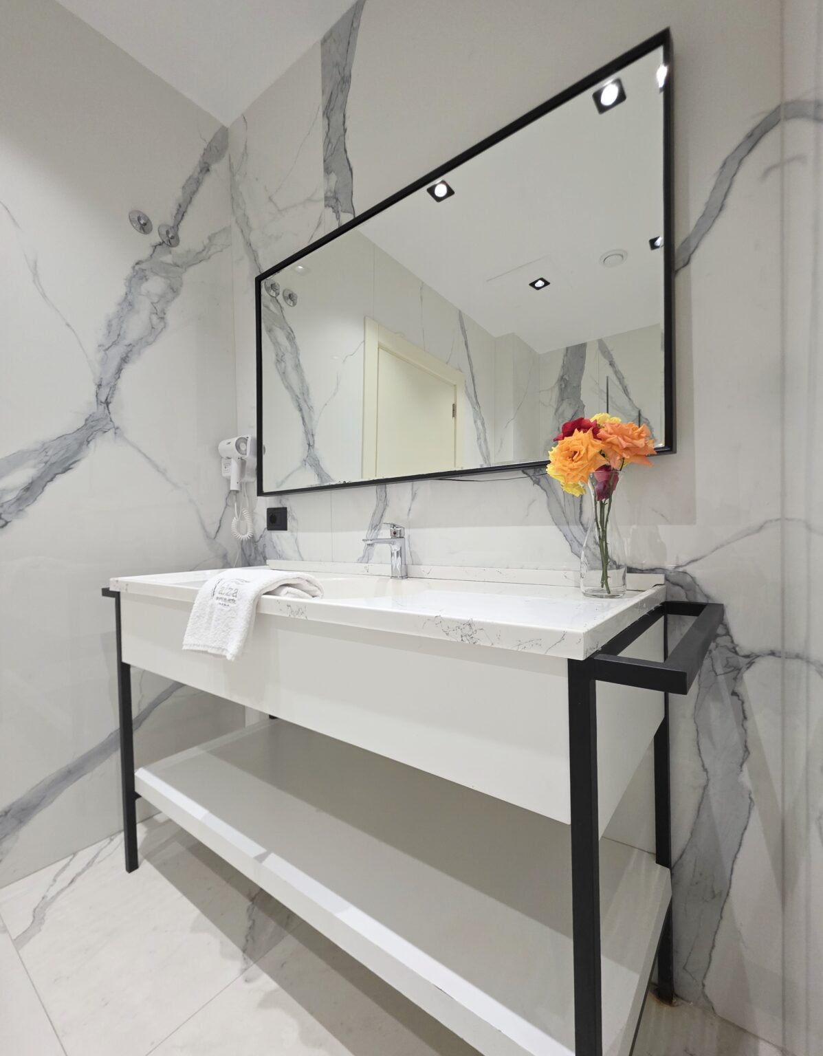 Marble-effect bathroom of the Double Deluxe Room with Extra Bed, basin on a black frame and large mirror