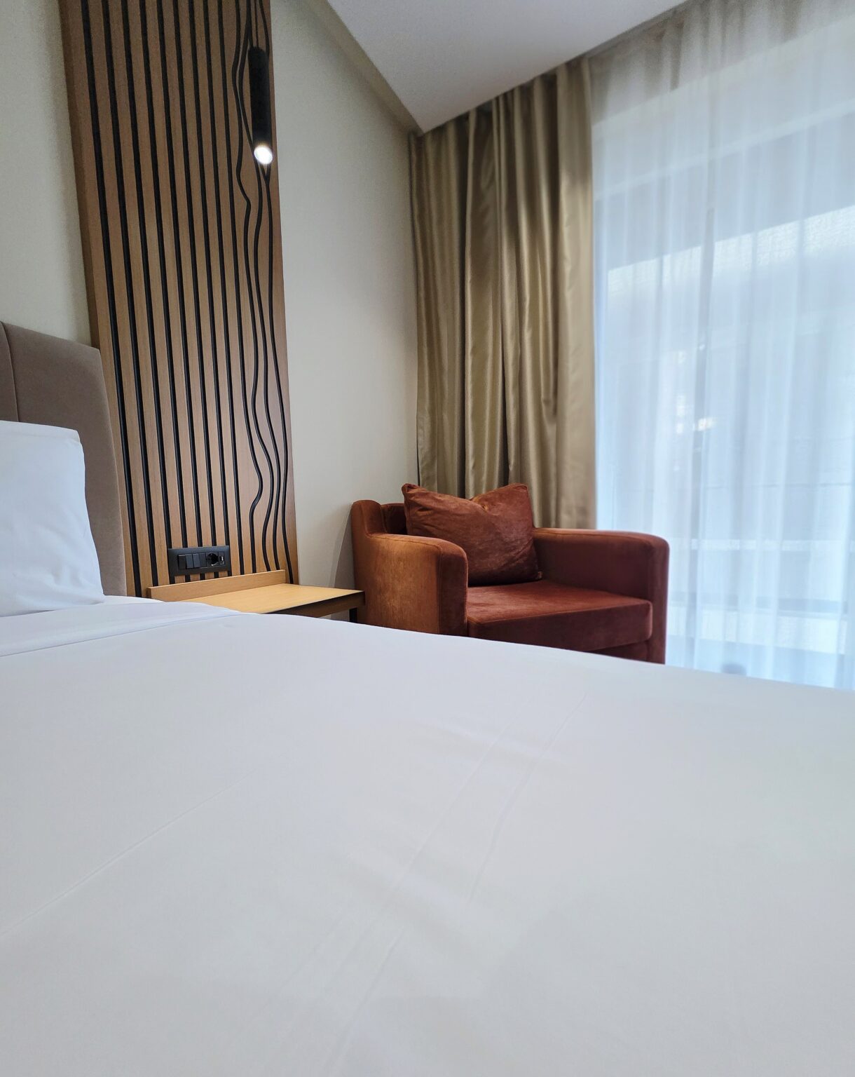 Rust velvet armchair by the window next to the bed in the Double Superior room