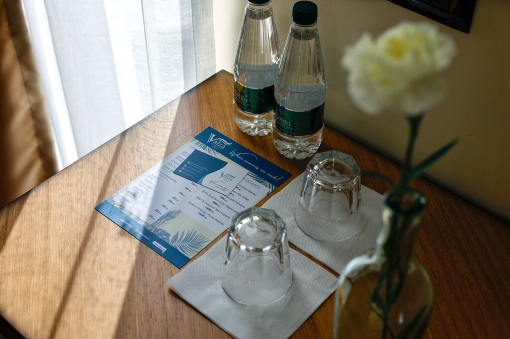 Minibar price list, water bottles and glasses on a wooden table in the Double Superior room