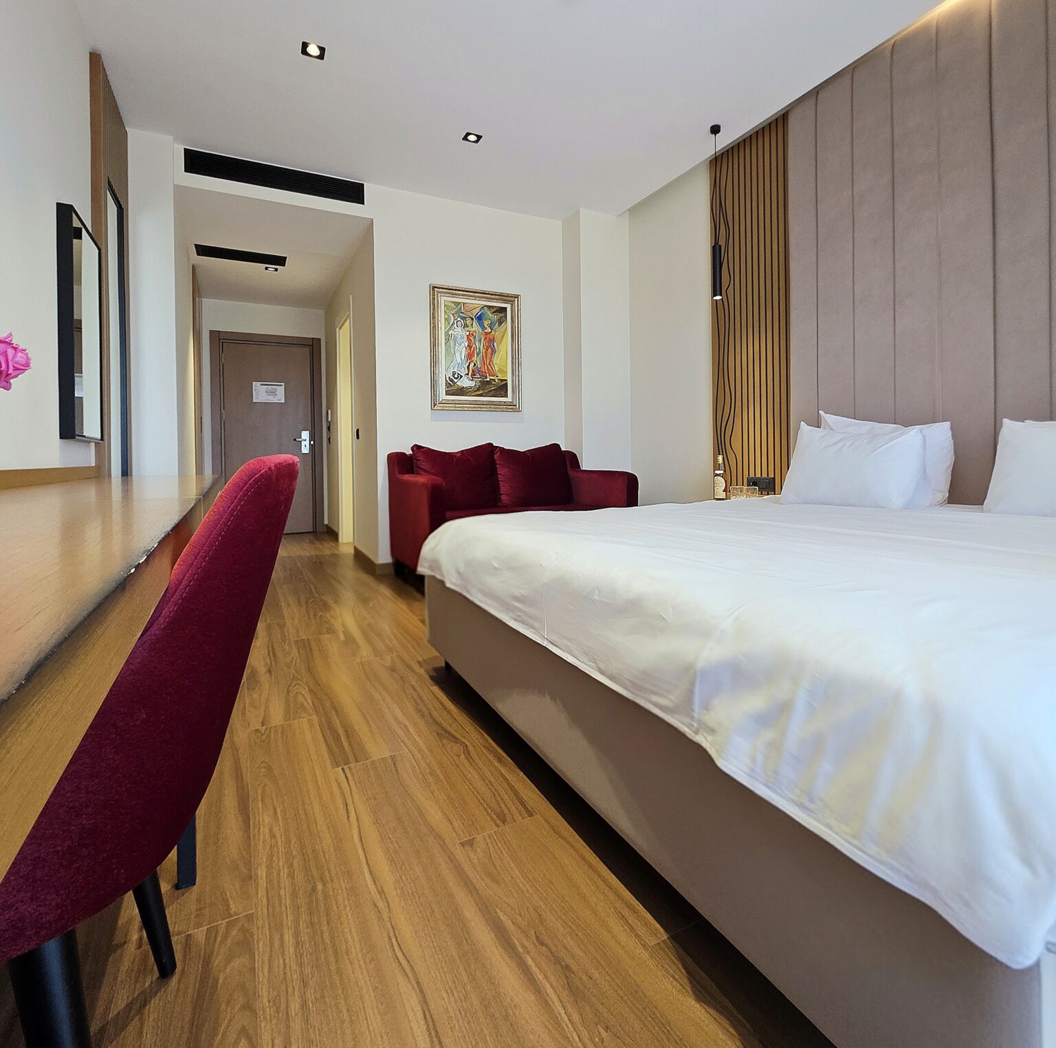Valza Suite seen from the desk, with red velvet chair, double bed and red sofa