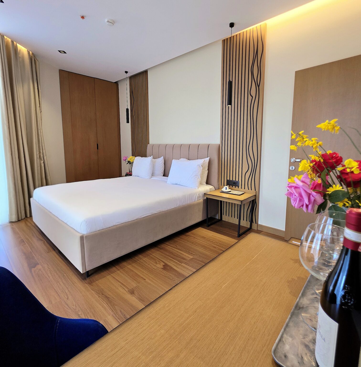 Master bedroom double bed with padded headboard, slatted oak wall panel, pendant light and bedside table