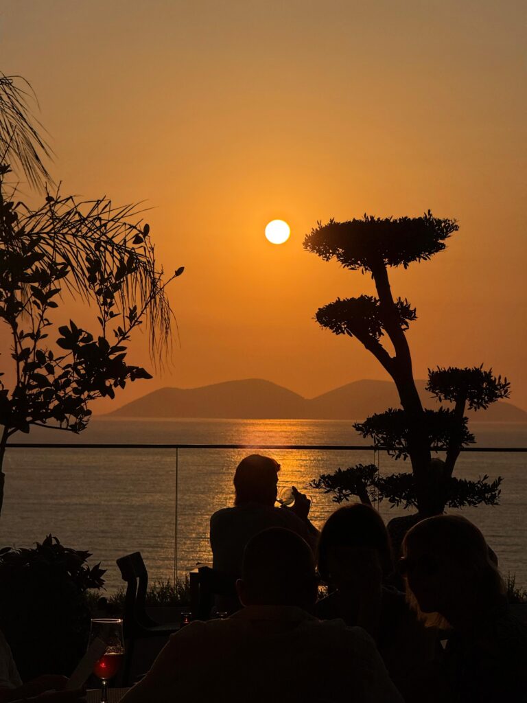 Guests enjoying a sunset drink at Valza Boutique Hotel in Vlorë with sea and island views.