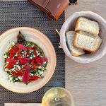 EdenRooftopRestaurant-Valza-01 Roasted pepper and crumbled cheese salad seen from above, with a bread basket and a glass of white wine