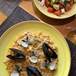 EdenRooftopRestaurant-Valza-08 Seafood risotto with mussels and clams on a yellow plate, beside a tomato, cucumber and cheese salad