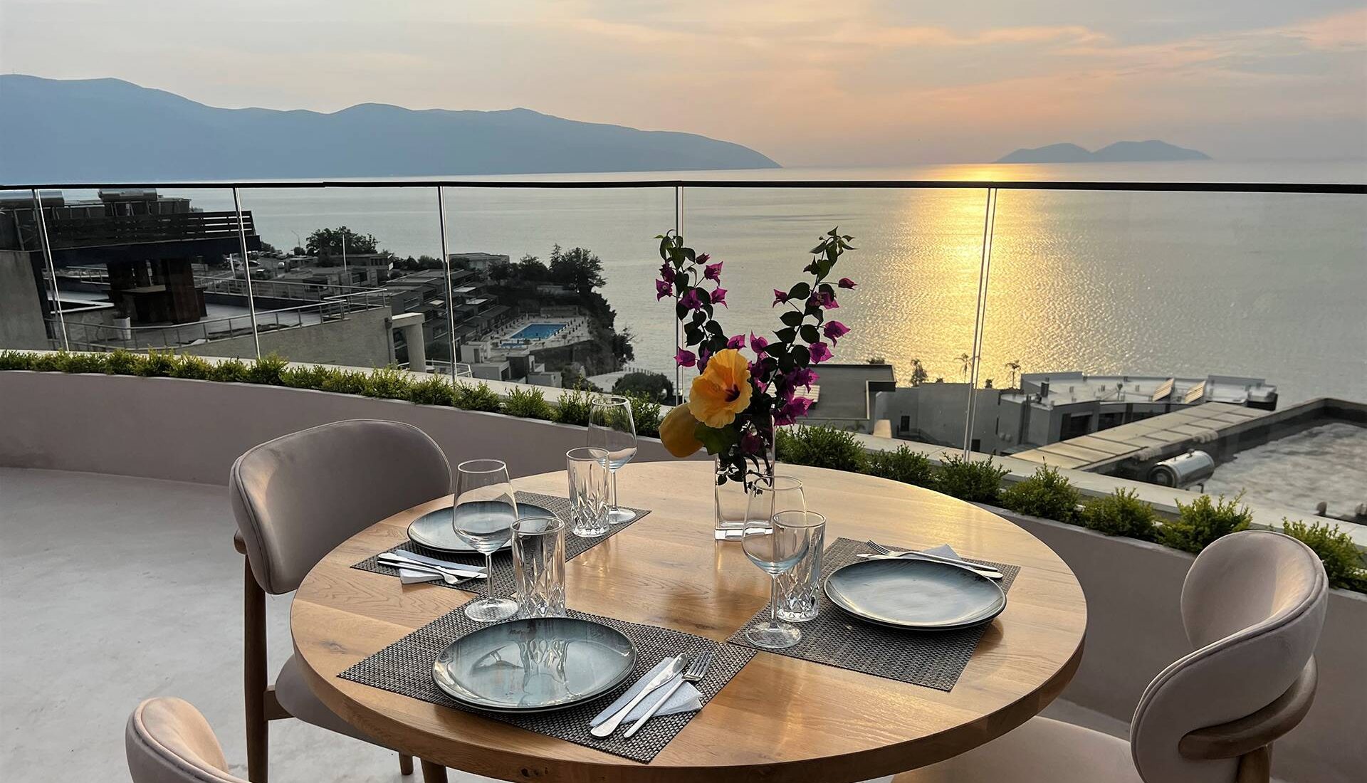 Eden by Valza rooftop table set for dinner at sunset, with a glass railing overlooking Vlorë Bay